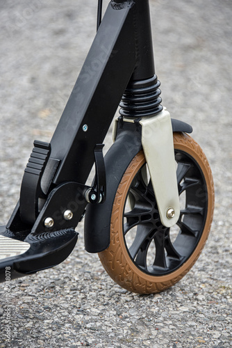 Front wheel of a scooter on asphalt. Close-up.