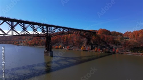 An aerial view over the Hudson River by the Walkway Over the Hudson State Park bridge on a sunny day in autumn. The camera dolly in and boom up towards the rusty steel footbridge. photo