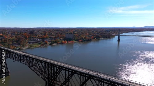 An aerial view of the Hudson River, flying over the Walkway Over the Hudson State Park bridge on a sunny day in autumn. The camera dolly in, pan left over it then dolly out from the large footbridge. photo