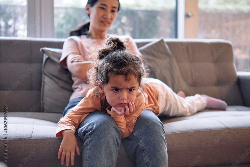 Girl lying on mother's lap in living room at home Girl lying on mother's lap in living room at home