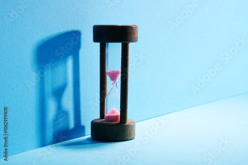 Hourglass with running sand over blue background photo