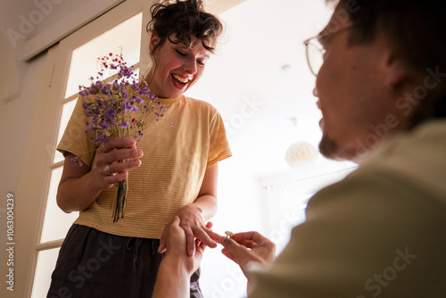 Excited woman getting engaged with man at home