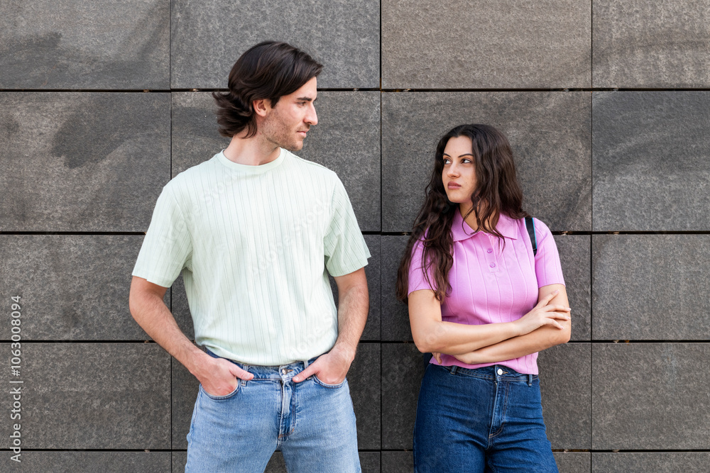 Furious couple looking at each other and standing in front of wall Furious couple looking at each other and standing in front of wall