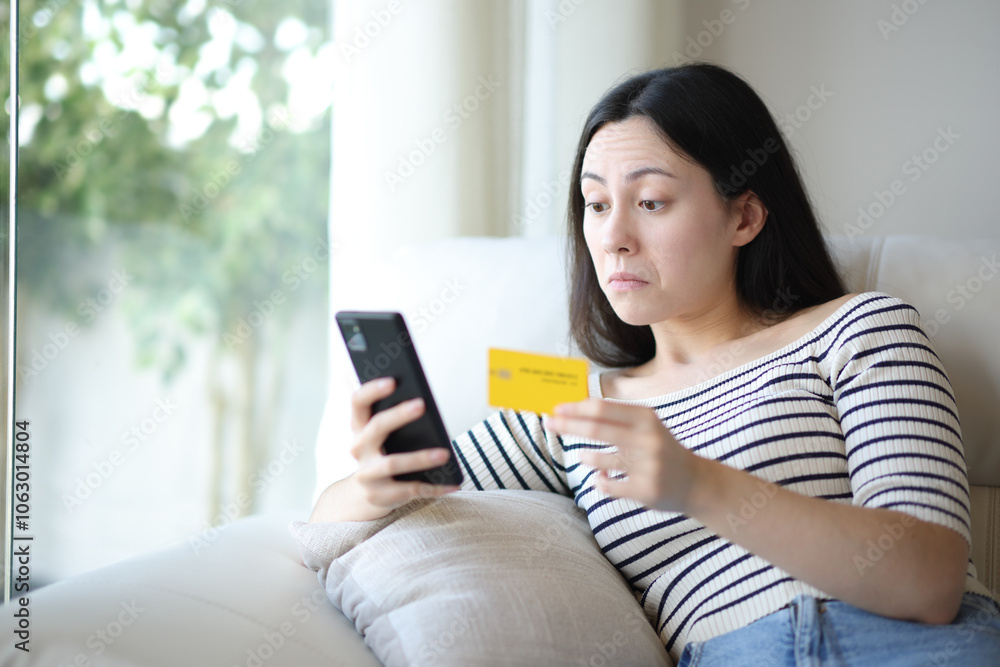 Perplexed asian woman buying online at home Perplexed asian woman buying online at home