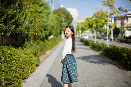 秋の昼の住宅街で散歩する小学生の女の子の姿