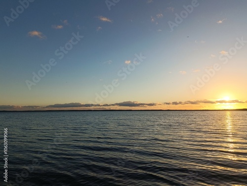 Red and yellow colored sunset over Rekyva lake. Sun set over lake. Some clouds are hangin in the sky. Blue yellow and red colored sky. Horizon over water. Saulelydis. Rekyvos ezeras. photo