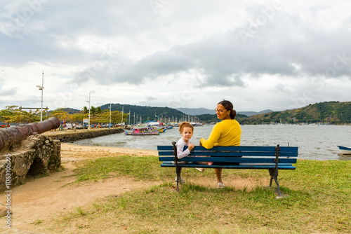 Wallpaper Mural Mother and daughter on a bench in the historic center of Paraty city and tourist in Rio de Janeiro, Brazil. Pier and Cannon, World Heritage Site on the Brazilian Coast Torontodigital.ca