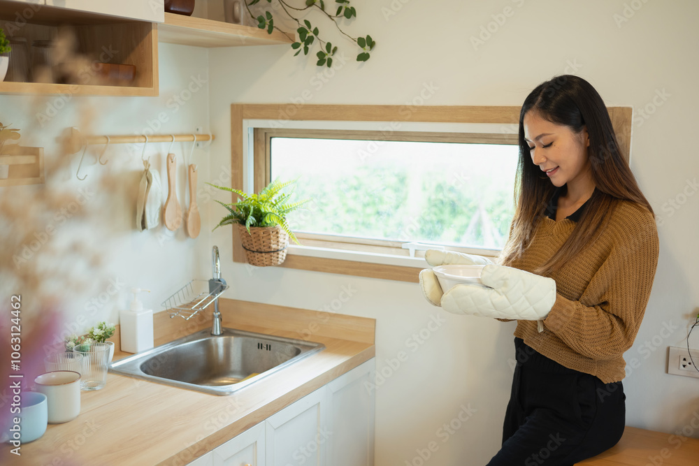Smiling woman holding a freshly Baked dish with oven mitts Smiling woman holding a freshly Baked dish with oven mitts