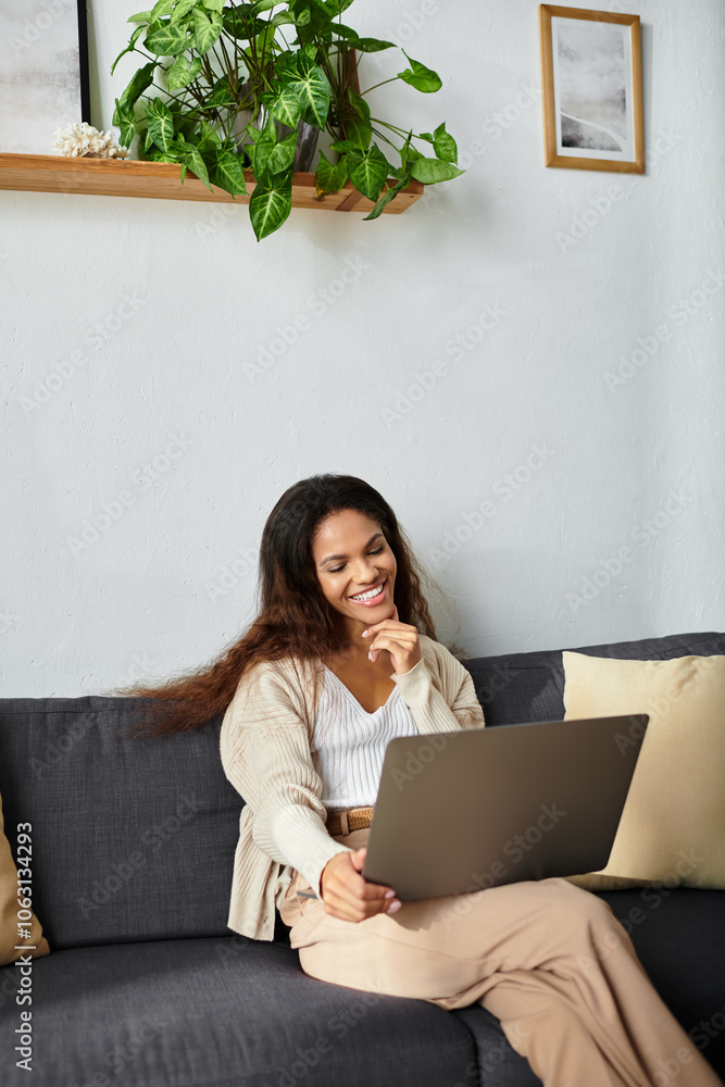 A cheerful woman sits on a soft couch, smiling while using her laptop in a warm and inviting space. A cheerful woman sits on a soft couch, smiling while using her laptop in a warm and inviting space.