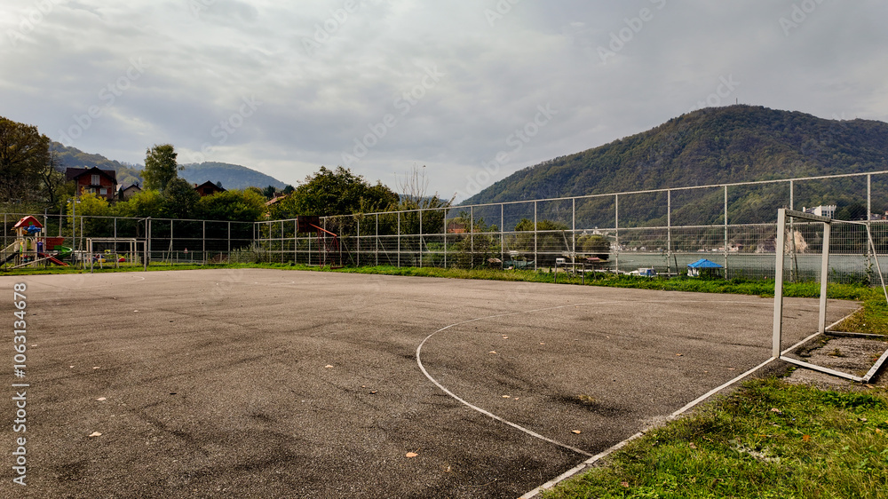 An empty outdoor basketball court surrounded by scenic mountains represents sports, leisure, and community engagement in a rural setting An empty outdoor basketball court surrounded by scenic mountains represents sports, leisure, and community engagement in a rural setting