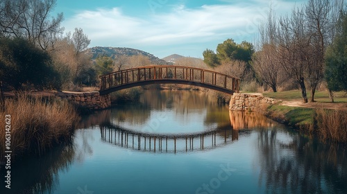 A tranquil landscape featuring a wooden bridge reflecting in calm waters, surrounded by trees and hills under a blue sky.