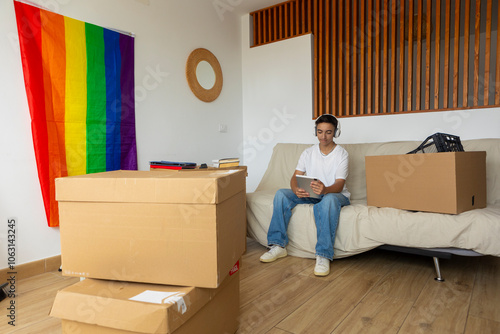 Trans man unpacking in new home with pride flag visible photo