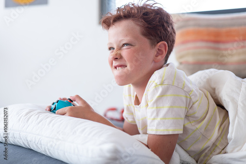 Young boy playing video games, looking away and smiling photo