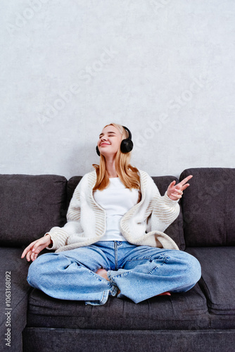 Fotografía A woman relaxes on the sofa, enjoying music through her headphones