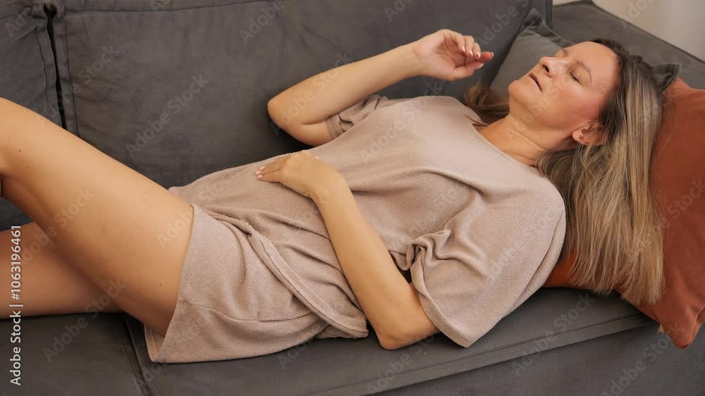 Woman lying on couch, visibly affected by headache, touching her head in discomfort. Persistent headache impacts her relaxation. Ideal for themes of pain, health, and managing frequent headache relief Woman lying on couch, visibly affected by headache, touching her head in discomfort. Persistent headache impacts her relaxation. Ideal for themes of pain, health, and managing frequent headache relief