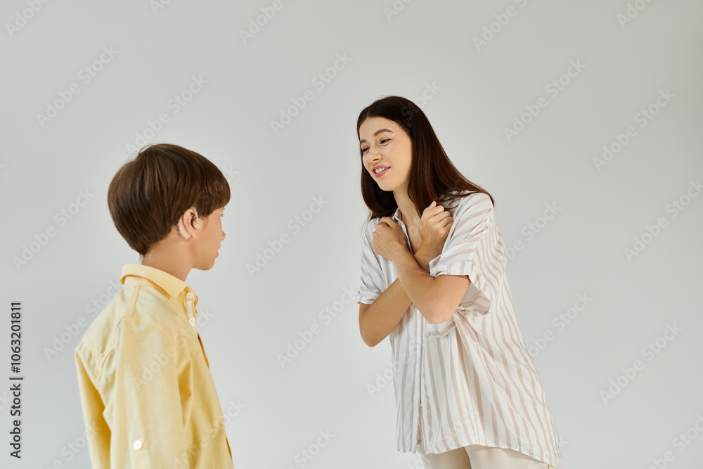 A supportive mother engages her hearing impaired son with warm gestures and smiles at home. A supportive mother engages her hearing impaired son with warm gestures and smiles at home.