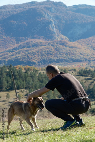 person with dog playing in the mountains