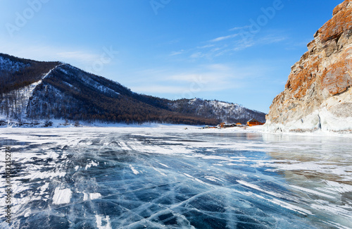 Baikal Lake on a sunny winter day. View from the ice road to the village of Uzury near the rocky shore of Olkhon Island. Winter ice travels and adventures photo