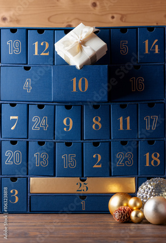 Advent calendar, blue boxes with numbers with gift and golden Christmas balls on a wooden background. Waiting, Christmas countdown. Vertical orientation.