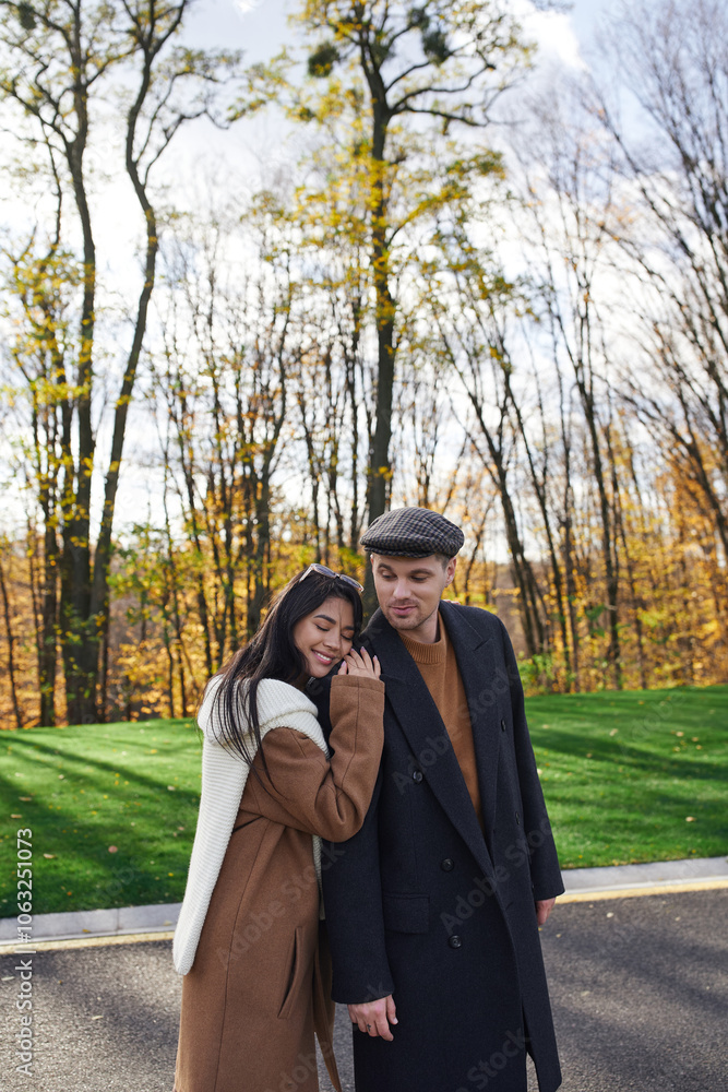 In a beautiful autumn setting, a couple enjoys an intimate moment, wrapped in cozy outfits. In a beautiful autumn setting, a couple enjoys an intimate moment, wrapped in cozy outfits.