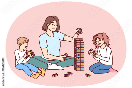 Woman babysitter together with kids plays constructor building tower of children blocks in kindergarten. Little boy and girl have good time and play educational games under supervision of babysitter