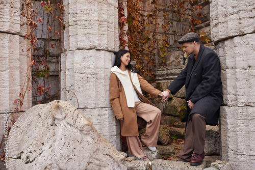 A couple enjoys a tender moment while surrounded by warm autumn colors and historic stone walls. photo