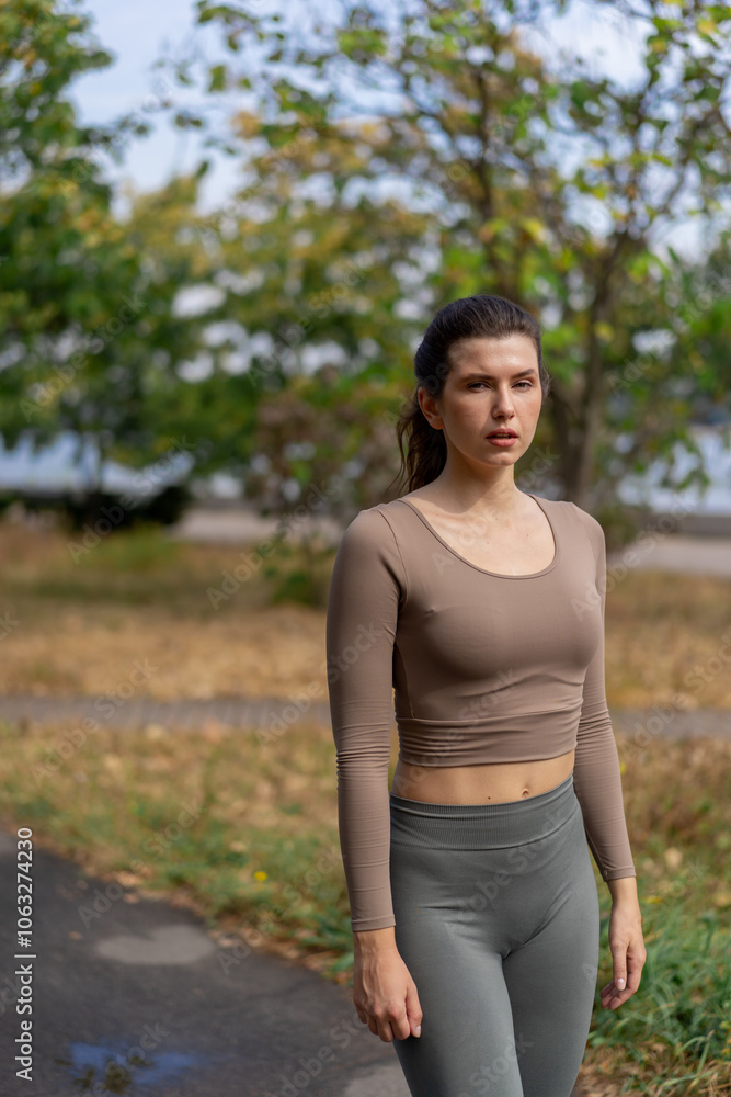 on the street on river embankment in the city center a brunette girl in a brown top and leggings poses for the camera healthy lifestyle on the street on river embankment in the city center a brunette girl in a brown top and leggings poses for the camera healthy lifestyle