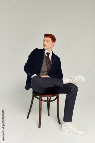 A young student with striking red hair showcases an elegant winter outfit in a cozy studio environment.