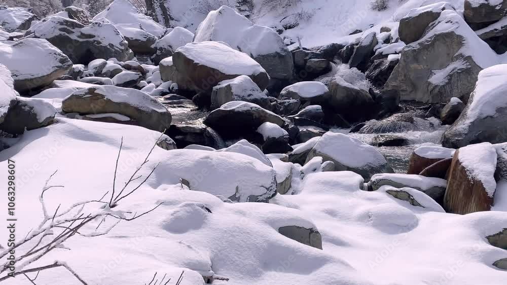 Cozy stream in winter in a snowy landscape flows through a stony stream bed - static shot Cozy stream in winter in a snowy landscape flows through a stony stream bed - static shot