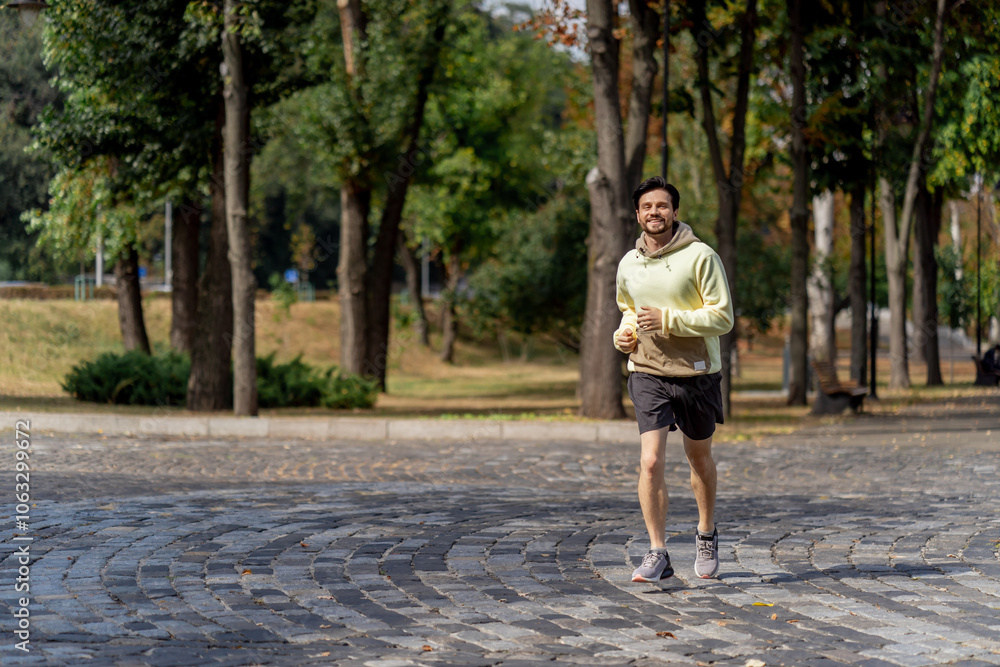 on the street in the park in the city center a handsome brunette guy in black shorts and yellow sweater on a morning jog on the street in the park in the city center a handsome brunette guy in black shorts and yellow sweater on a morning jog