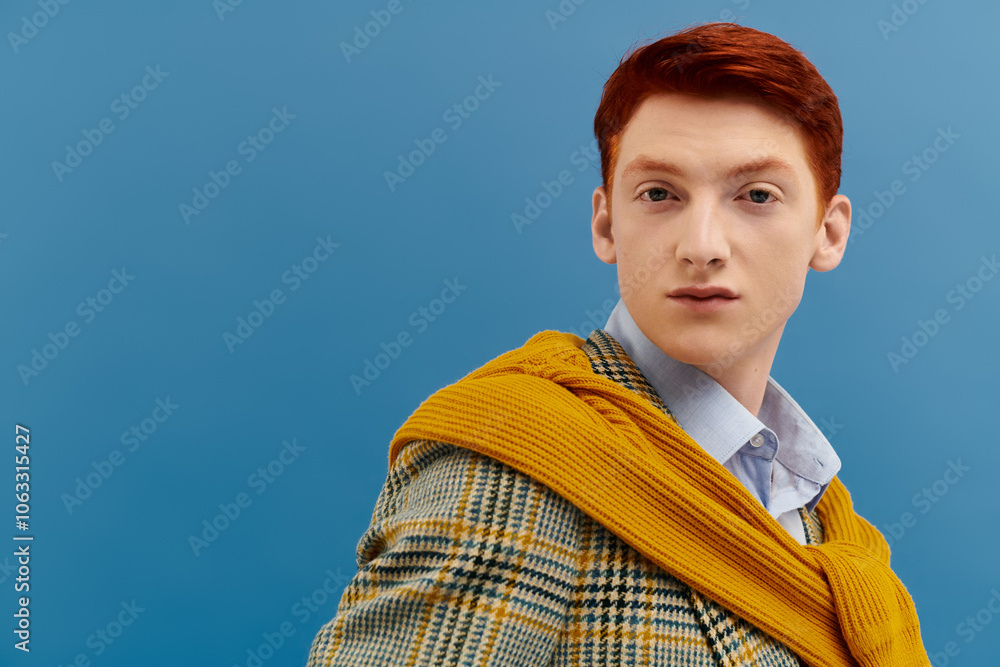 A stylish man with striking red hair displays a fashionable layered outfit in a studio backdrop. A stylish man with striking red hair displays a fashionable layered outfit in a studio backdrop.