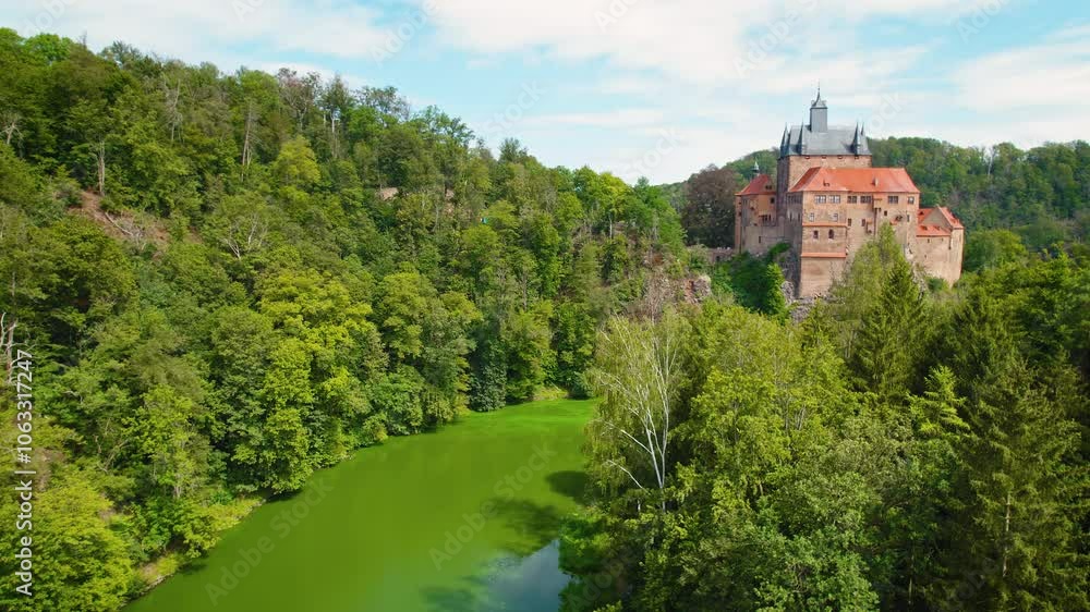 Historic castle perched on a hill surrounded by dense green forest and calm river, evoking a fairy-tale charm. Historic castle perched on a hill surrounded by dense green forest and calm river, evoking a fairy-tale charm.