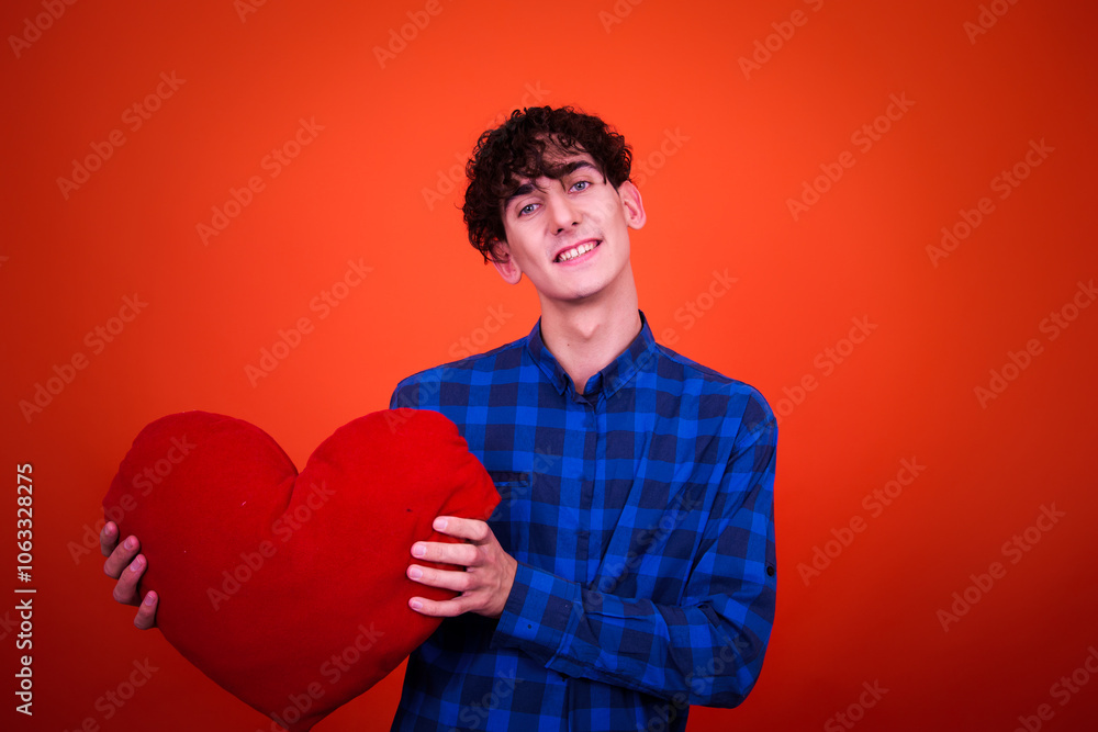 A funny young attractive guy with a curly hairstyle poses in the studio.