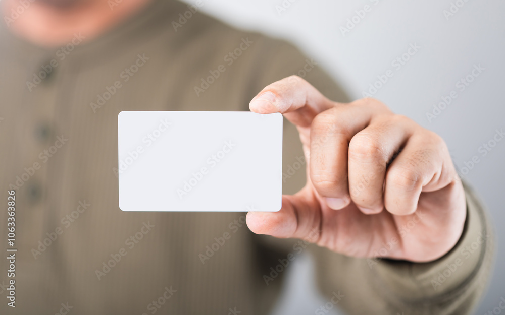 Thai man holds a blank white name card, symbolizing new opportunities and personal branding in a professional setting Thai man holds a blank white name card, symbolizing new opportunities and personal branding in a professional setting