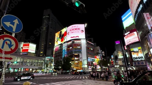 Bustling Shibuya crossing in Tokyo at night with bright neon signs and crowds of pedestrians