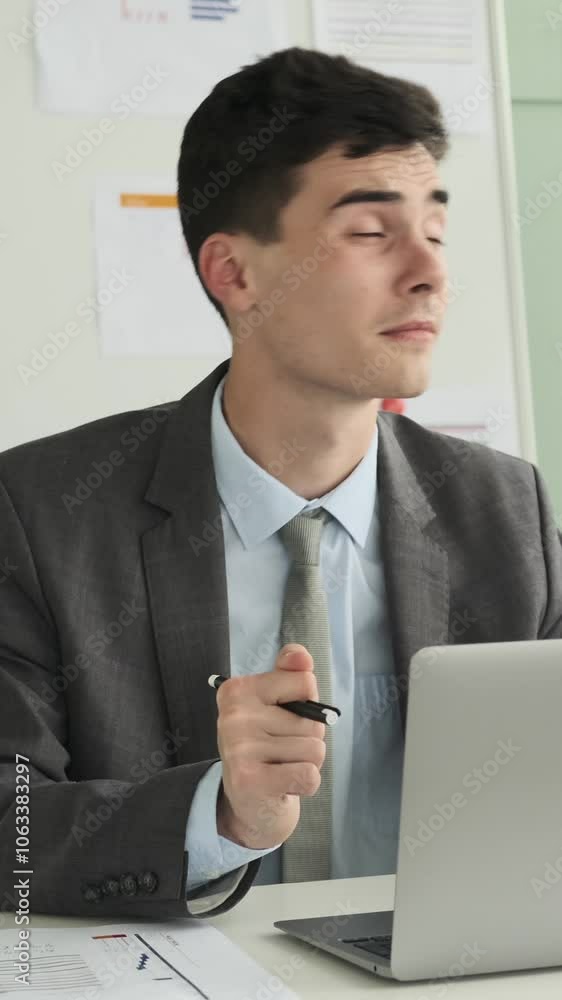 Cheerful young adult Caucasian businessman dancing and singing to music while working with laptop in the modern office. Vertical video. Cheerful young adult Caucasian businessman dancing and singing to music while working with laptop in the modern office. Vertical video.