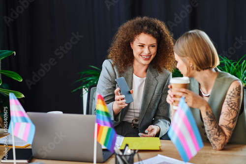 Bild auf Leinwand Two coworkers engage joyfully at their desks, surrounded by pride flags and positive energy