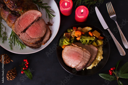Whole round roast beef and Christmas decorations. New Year dinner table. High angle view