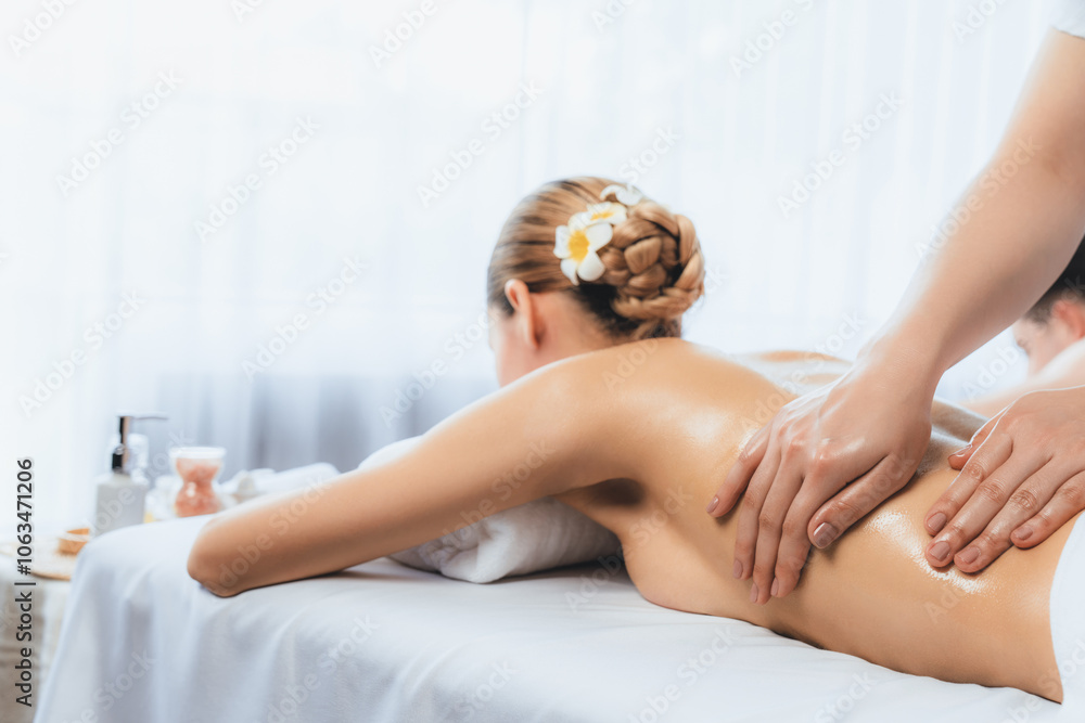 Fototapeta premium Caucasian couple customer enjoying relaxing anti-stress spa massage and pampering with beauty skin recreation leisure in day light ambient salon spa at luxury resort or hotel. Quiescent