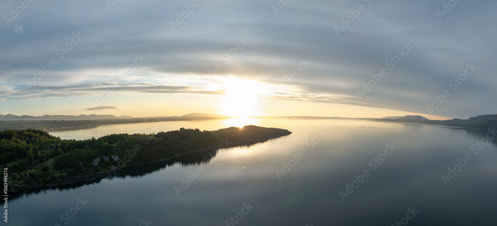 Fototapeta premium Dramatic panorama landscape of peninsula by calm waters of a lake at sunset