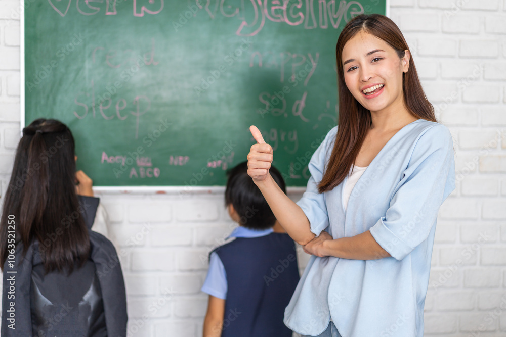 Female teacher smiling confidently in front of blackboard with students learning in classroom, educational environment, happy teacher, school atmosphere, classroom activity, teaching and learning Female teacher smiling confidently in front of blackboard with students learning in classroom, educational environment, happy teacher, school atmosphere, classroom activity, teaching and learning