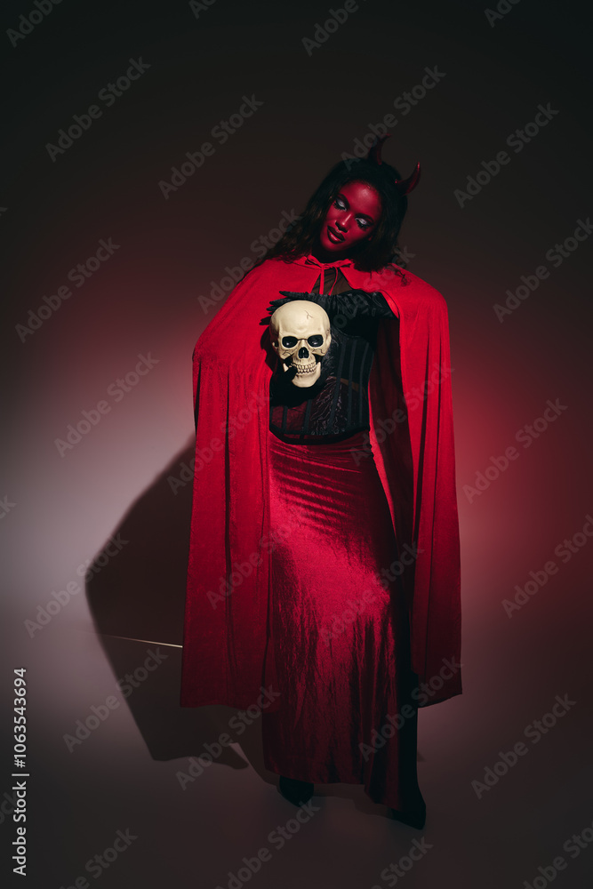A radiant woman showcases her Halloween costume, exuding confidence with a striking skull accessory. A radiant woman showcases her Halloween costume, exuding confidence with a striking skull accessory.