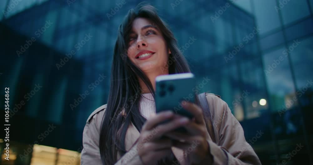 Camera moving closer to Caucasian girls face. Woman looking at her smartphone screen. Smiling while texting and chatting with boyfriend. Remotely communicating with someone after work. Night in city. Camera moving closer to Caucasian girls face. Woman looking at her smartphone screen. Smiling while texting and chatting with boyfriend. Remotely communicating with someone after work. Night in city.