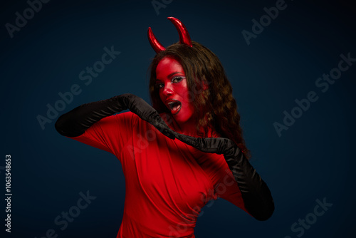 A stunning woman displays her vibrant red Halloween costume and striking accessories.