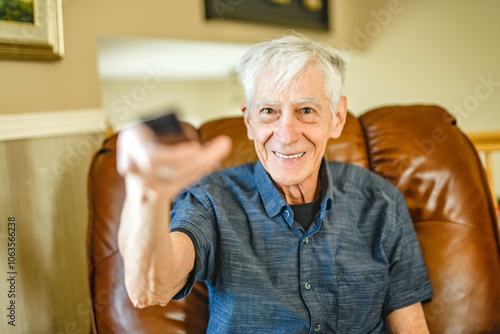 Portrait of retired senior man standing at home watching tv