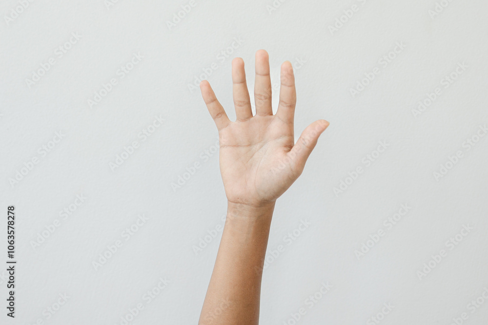 A hand is raised in the air, with the fingers spread out A hand is raised in the air, with the fingers spread out