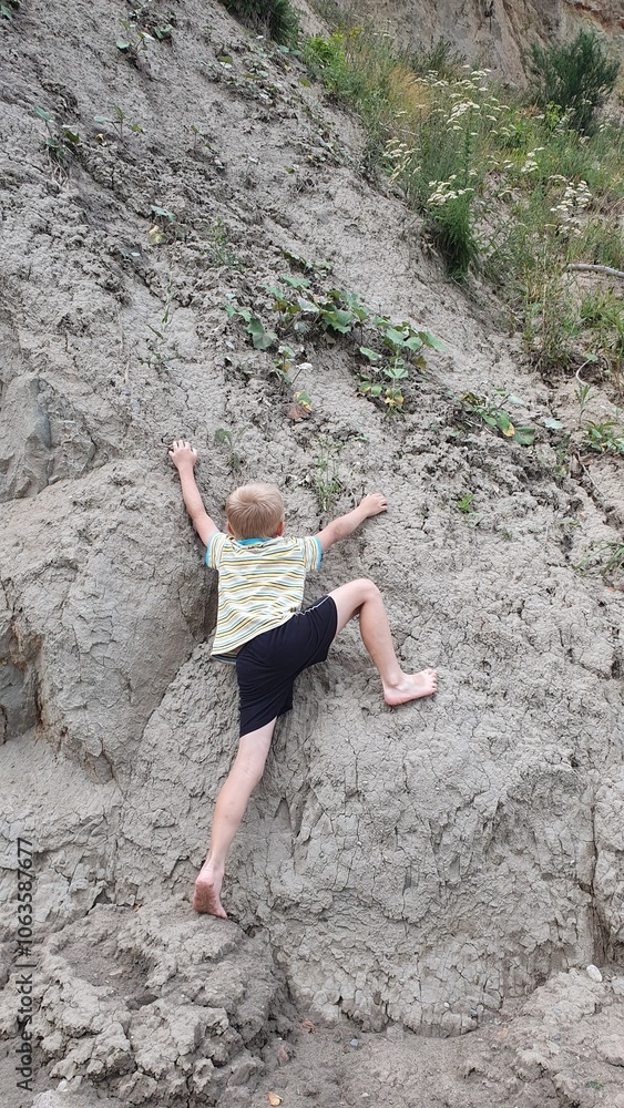 Obraz premium Dziecko wspinające się na klif podczas wakacji.