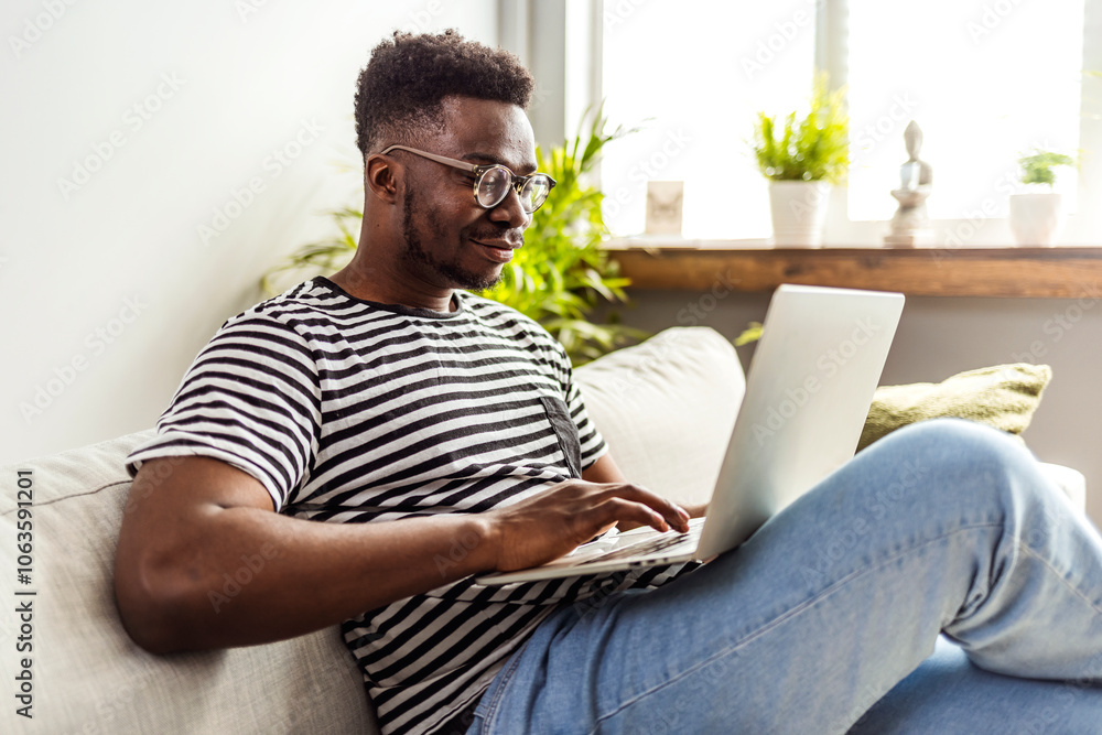 Smiling Man Relaxing on Couch While Using a Laptop Smiling Man Relaxing on Couch While Using a Laptop