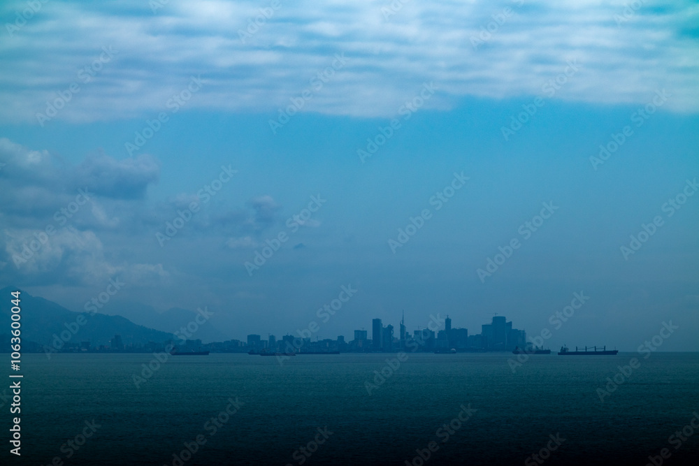 A blurry city skyline looms over the shimmering surface of the water A blurry city skyline looms over the shimmering surface of the water