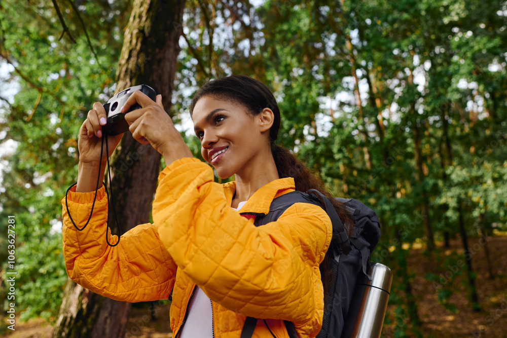 A young African American woman enjoys hiking through a colorful forest, capturing the stunning autumn scenery. A young African American woman enjoys hiking through a colorful forest, capturing the stunning autumn scenery.